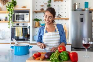 magnifique Jeune femme supporter à moderne cuisine hacher des légumes préparer Frais légume salade pour dîner ou déjeuner, Jeune femme cuisine à Accueil faire petit déjeuner suivre en bonne santé régime, végétarien concept photo