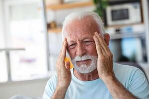 mal de tête. Sénior homme Souffrance de migraine douleur masser les temples séance à maison. soins de santé, santé problèmes dans plus âgée âge concept photo
