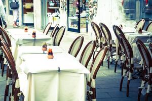 en bois les tables sur étroit rue parmi typique coloré Maisons et petit pont dans Venise, Italie. photo