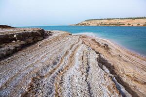 vue de mort mer littoral à le coucher du soleil temps dans Jordan. sel cristaux à le coucher du soleil. mort mer paysage avec minéral structures. photo