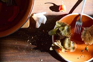 Haut vue sale vide assiette avec pain les miettes et le du repos de inachevé nourriture près une argile tajine plat sur une en bois table photo