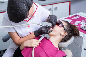 dentiste examiner les dents de une Jeune femme patient dans une dentaire clinique. dentisterie concept. dentiste et patient dans le dentaire bureau. photo