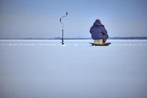 pêcheur profiter une journées pêche sur le la glace photo