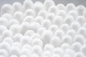 macro vue de blanc coton oreille nettoyage bourgeons arrangé dans blanc arrière-plan bien dans une récipient photo