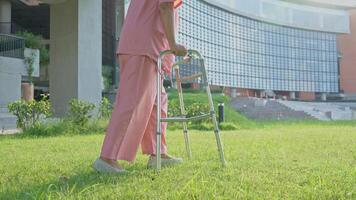 un vieux personnes âgées asiatique femme les usages une marcheur et en marchant dans le arrière-cour dans hôpital. physique thérapie, réhabilitation et Sénior santé Assurance concept. médical pour Sénior se soucier l'arthrose. photo