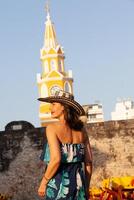 magnifique femme portant le traditionnel colombien chapeau appelé sombrero vueltiao à le l'horloge la tour sur le historique des rues de le Carthagène de Indes fortifiée ville photo