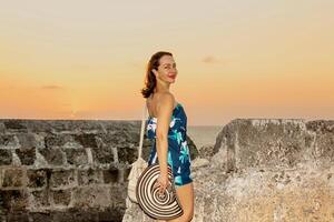 magnifique femme avec le traditionnel colombien chapeau appelé sombrero vueltiao et une traditionnel mochila à le historique des murs de Carthagène de Indes photo