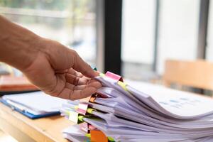 une Jeune secrétaire reçoit une pile de les documents à trouver important information pour le entreprise directeur à utilisation dans une réunion. le concept de découverte important les documents de piles de chevauchement les documents photo