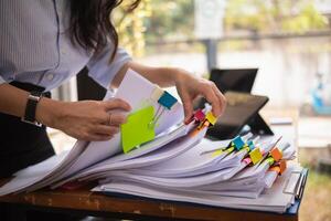 secrétaire est recherche par pile de important les documents sur Bureau table livrer leur à directeur pour présentation dans temps à réunion. concept de difficulté découverte information de piles de document photo