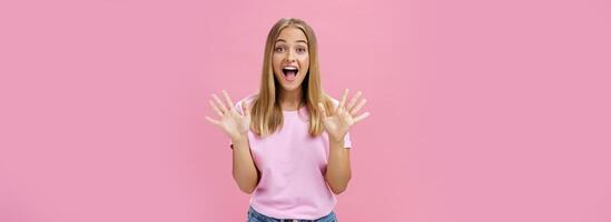 amusé et surpris excité attrayant Jeune caucasien femelle dans décontractée T-shirt faire des gestes avec propager les doigts plus de poitrine souriant largement avec stupéfaction à la recherche à caméra récit impressionnant nouvelles photo