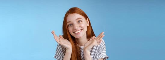 idiot mignonne sincère Jeune européen gingembre fille bleu yeux haussant les épaules tenir mains douteux propager près visage basculant tête s'excuser affectueux dire Pardon en retard fabrication boiteux des excuses, permanent bleu Contexte photo