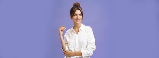 féminin et élégant moderne charmant fille avec écarté les dents et bouton posant dans branché blanc chemisier et rond des boucles d'oreilles regarder la gauche charmé et sensuel avec mignonne sourire plus de violet Contexte photo