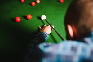 Jeune Beau homme penché plus de le table tandis que en jouant billard photo