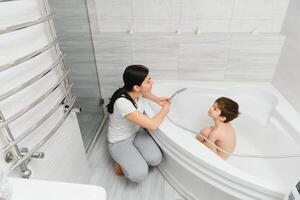 mère la lessive peu fils dans salle de bains photo