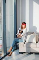 de bonne humeur Jeune femme en portant sa gros chiot avec noir nez et en riant. intérieur portrait de souriant fille posant avec français bouledogue photo