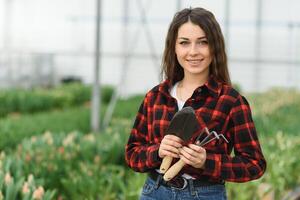 magnifique Jeune souriant fille, ouvrier avec fleurs dans serre. concept travail dans le serre, fleurs. photo