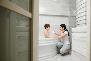 mère la lessive peu fils dans salle de bains photo