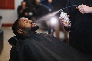 noir homme dans le salon de coiffure. mignonne noir homme fait du une la Coupe de cheveux dans le africain salon. cheveux style. la Coupe de cheveux pour adultes. photo