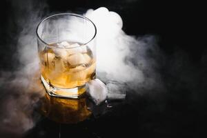 whisky avec la glace sur noir Contexte avec fumée photo