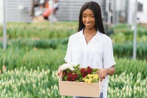 agriculture gestion. souriant africain américain fille fait du photo de fleurs plantation dans serre, côté voir, gratuit espace