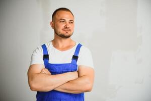 portrait de Jeune bricoleur permanent sur blanc Contexte avec copie espace. dépanneur portant vêtements de travail uniforme. photo