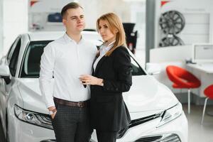 Jeune couple souriant à auto salle d'exposition. photo