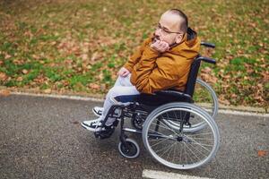 portrait de paraplégique handicapé homme dans fauteuil roulant dans parc. il est réfléchi et relaxant. photo