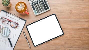 une soigneusement organisé espace de travail avec une tablette avec une Vide filtrer, financier graphiques, une calculatrice, et une tasse de café sur une en bois surface. photo