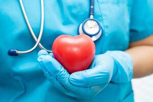 médecin tenant un coeur rouge dans la salle d'hôpital, concept médical solide et sain. photo