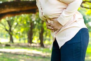 personnes âgées femme en marchant dans le parc elle avait aigu abdominal douleur. c'est cholécystite. concept de problèmes de gastro-intestinal tract dans le âgé. santé se soucier. copie espace photo