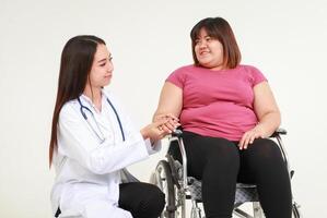 femelle médecin traiter un obèse femme séance dans une fauteuil roulant. poids perte concept. santé se soucier pour obèse personnes. médical prestations de service photo