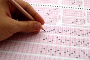 examen, une main prise une tester avec une crayon plus de un optique lecteur. futur anxiété. incertitude. photo