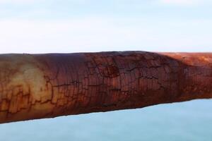 une rouillé clôture avec une bleu mer dans le arrière-plan.rusty le fer balustrade, magnifique mer et ciel paysage vue entre rouillé balustrade écart. photo