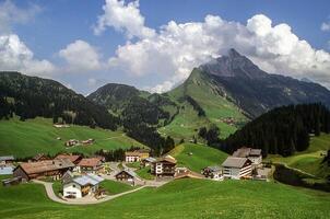 une village dans le montagnes avec vert herbe et montagnes photo