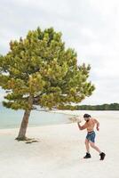 Jeune musclé homme exercice sur le plage, Jeune musclé homme Faire musculation des exercices sur le plage, athlétique Jeune homme sur le plage photo