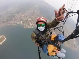 parapente dans le montagnes, le deux les personnes sur le Haut de le montagne, le parachutistes sont en volant avec une parachute photo