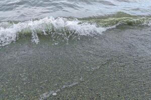 l'eau gouttes sur le plage, proche en haut de une le sable sur le plage photo