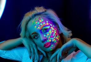 portrait de une femme avec peint affronter, femme avec uv maquillage dans studio, portrait de une femme dans carnaval masque, le femme est décoré dans une ultra-violet poudre photo