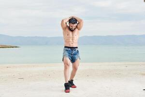 Jeune musclé homme exercice sur le plage, Jeune musclé homme Faire musculation des exercices sur le plage, athlétique Jeune homme sur le plage photo