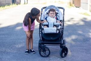 une petit sœur avec sa bébé garçon frère dans une fauteuil roulant photo