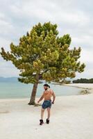 Jeune musclé homme exercice sur le plage, Jeune musclé homme Faire musculation des exercices sur le plage, athlétique Jeune homme sur le plage photo