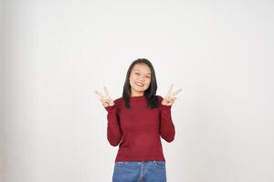 Jeune asiatique femme dans rouge T-shirt souriant et montrant paix ou la victoire signe montrant isolé sur blanc Contexte photo