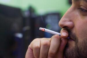 homme d'affaire fumeur cigarette dans le sien bureau, Jeune homme fumeur cigarette photo