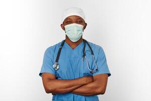Chirurgien noir médecin homme en manteau bleu bonnet blanc et masque de chirurgien isolé sur fond blanc photo