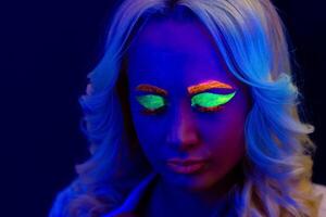 portrait de une femme avec peint affronter, femme avec uv maquillage dans studio, portrait de une femme dans carnaval masque, le femme est décoré dans une ultra-violet poudre photo