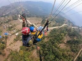 parapente dans le montagnes, le deux les personnes sur le Haut de le montagne, le parachutistes sont en volant avec une parachute photo