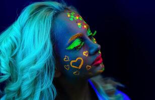 portrait de une femme avec peint affronter, femme avec uv maquillage dans studio, portrait de une femme dans carnaval masque, le femme est décoré dans une ultra-violet poudre photo