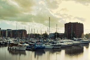 tranquille Marina avec bateaux et yachts amarré à coucher de soleil, avec calme l'eau et Urbain bâtiments dans le Contexte. photo