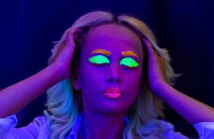 portrait de une femme avec peint affronter, femme avec uv maquillage dans studio, portrait de une femme dans carnaval masque, le femme est décoré dans une ultra-violet poudre photo