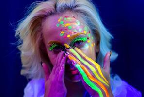 portrait de une femme avec peint affronter, femme avec uv maquillage dans studio, portrait de une femme dans carnaval masque, le femme est décoré dans une ultra-violet poudre photo